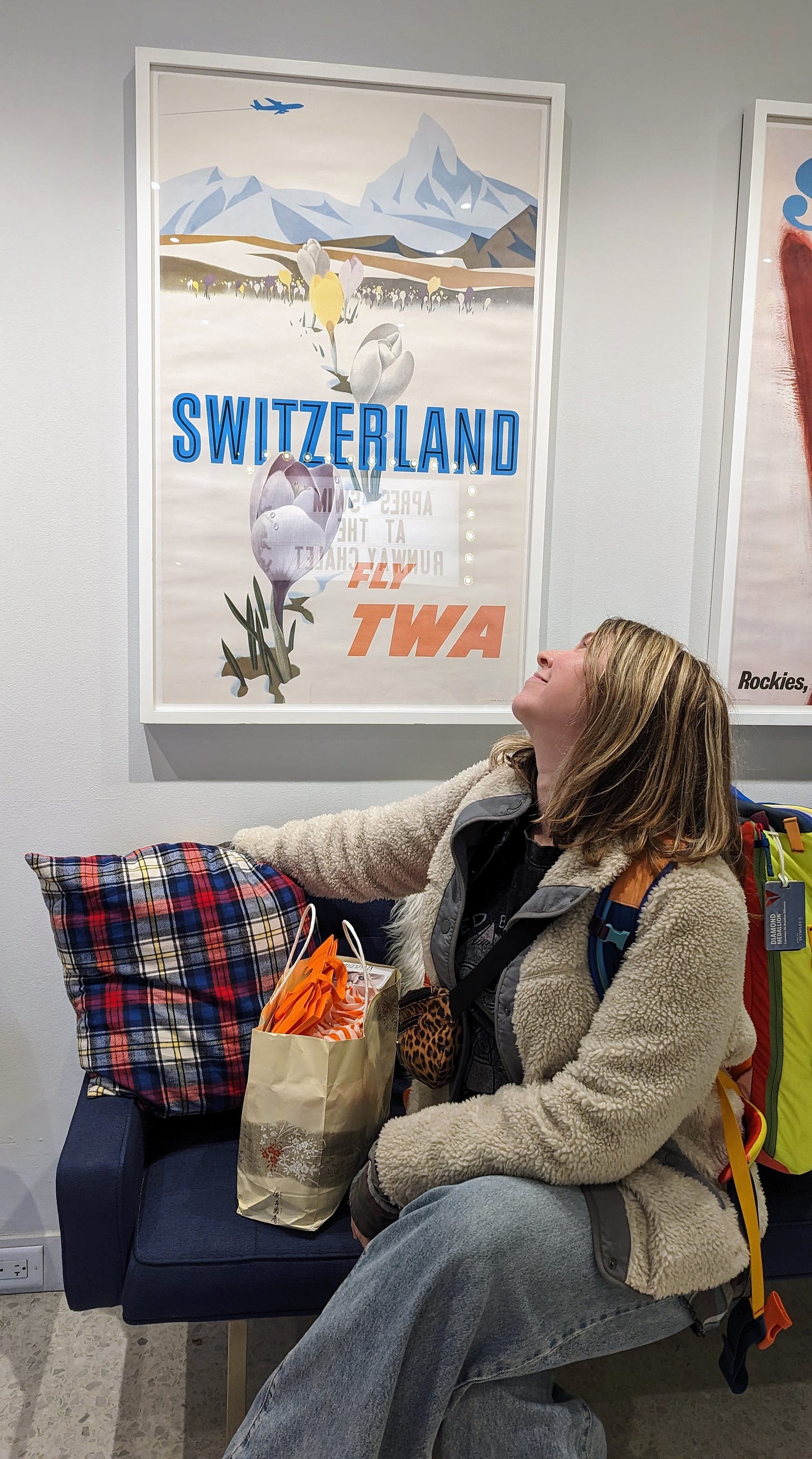 woman in front of vintage TWA advertising poster advertising a flight to switzerland