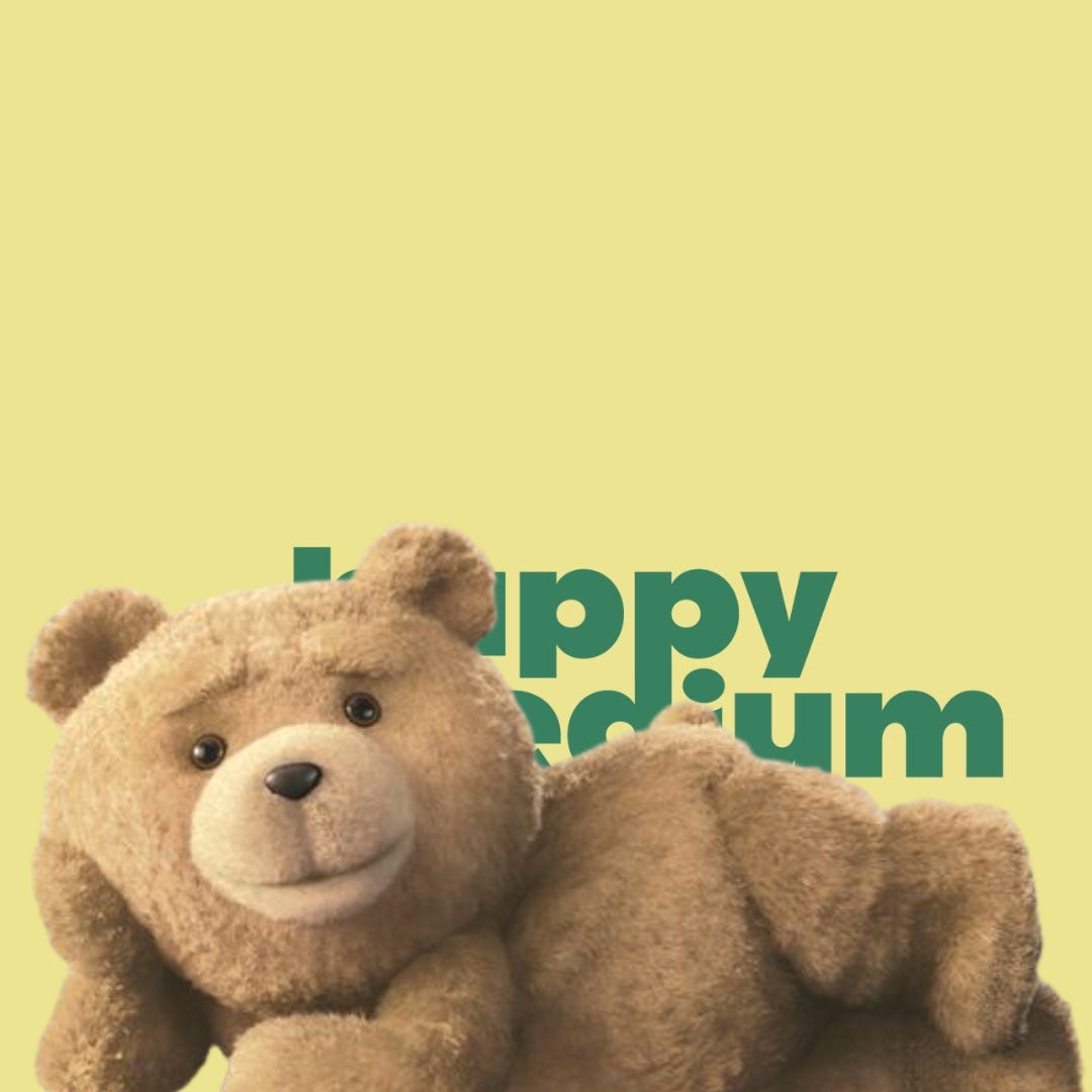 The teddy bear from the film "Ted" lies in front of the Happy Medium Club logo.