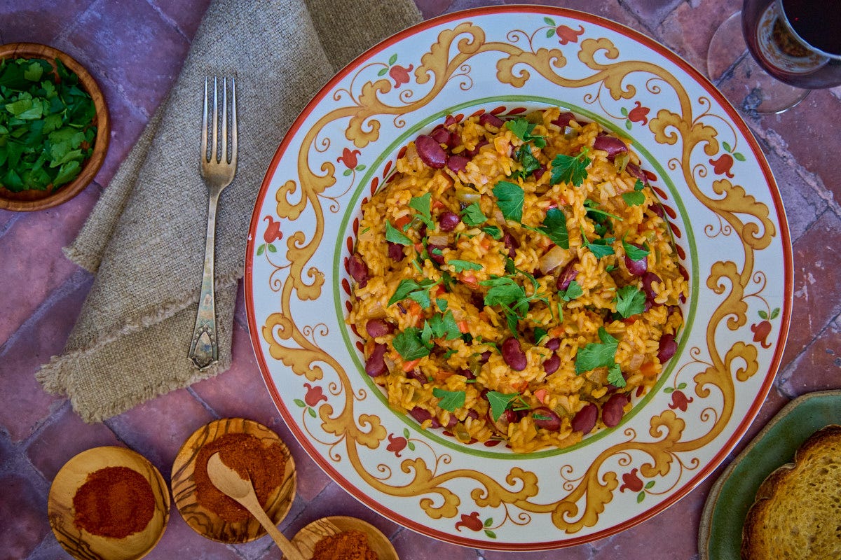 Bowl of traditional Portuguese arroz de feijão (beans and rice) with herbs, bowls of ground pepper, wine, and toasted bread