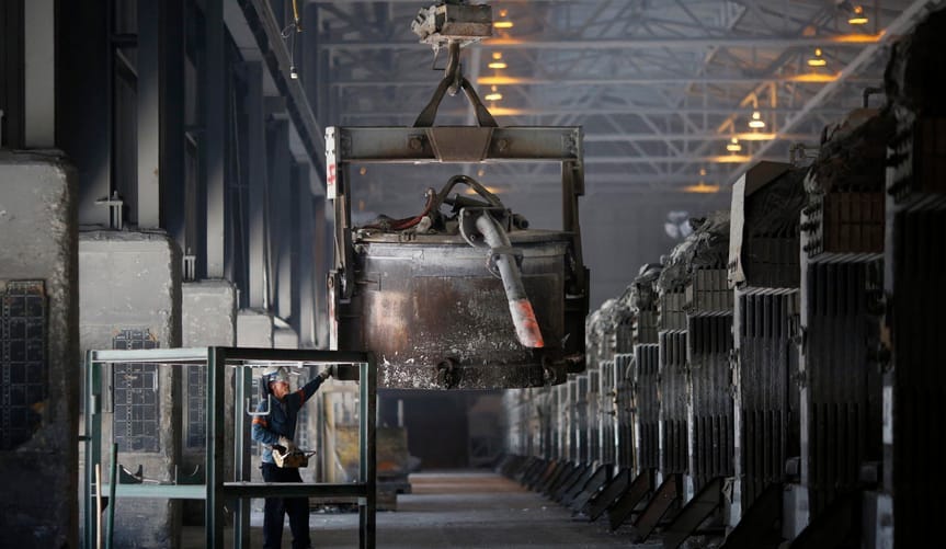 A plant worker uses a crane to lift a cask of molten aluminum along a potline at Century Aluminum Company's Hawesville plant