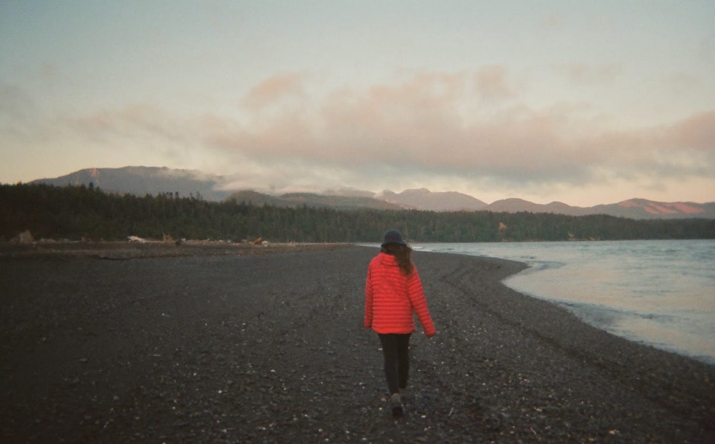 Brunette in red jacket walks on northwest beach