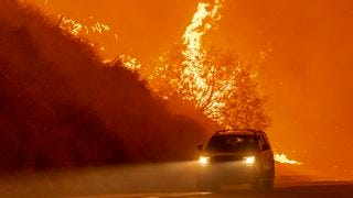 A car driving by a raging wildfire