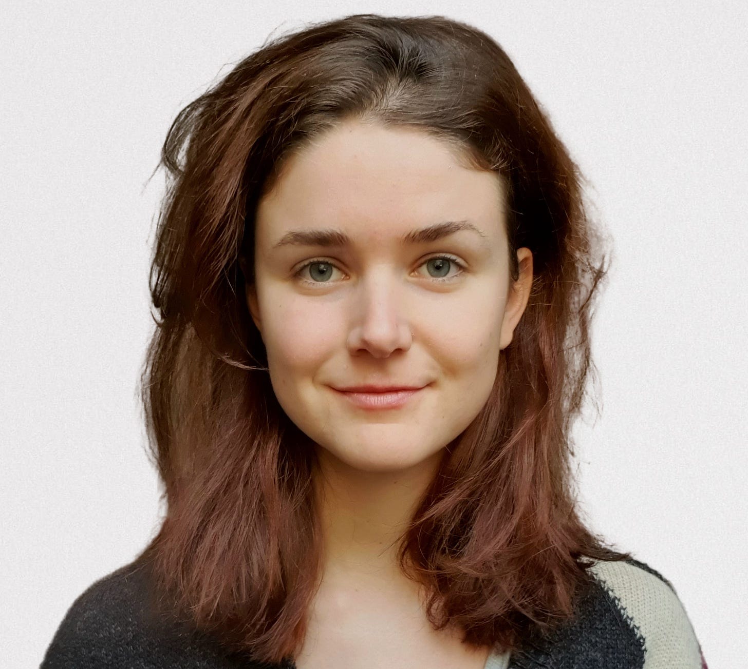 Headshot of young white woman with long brown hair smiling directly at camera