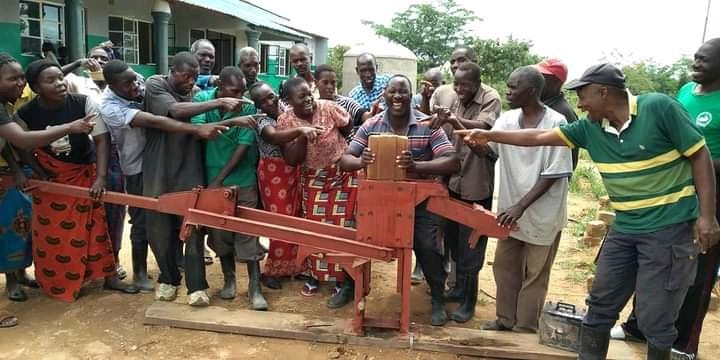 CLAO and community members posingw ith a hand-powered brick press 