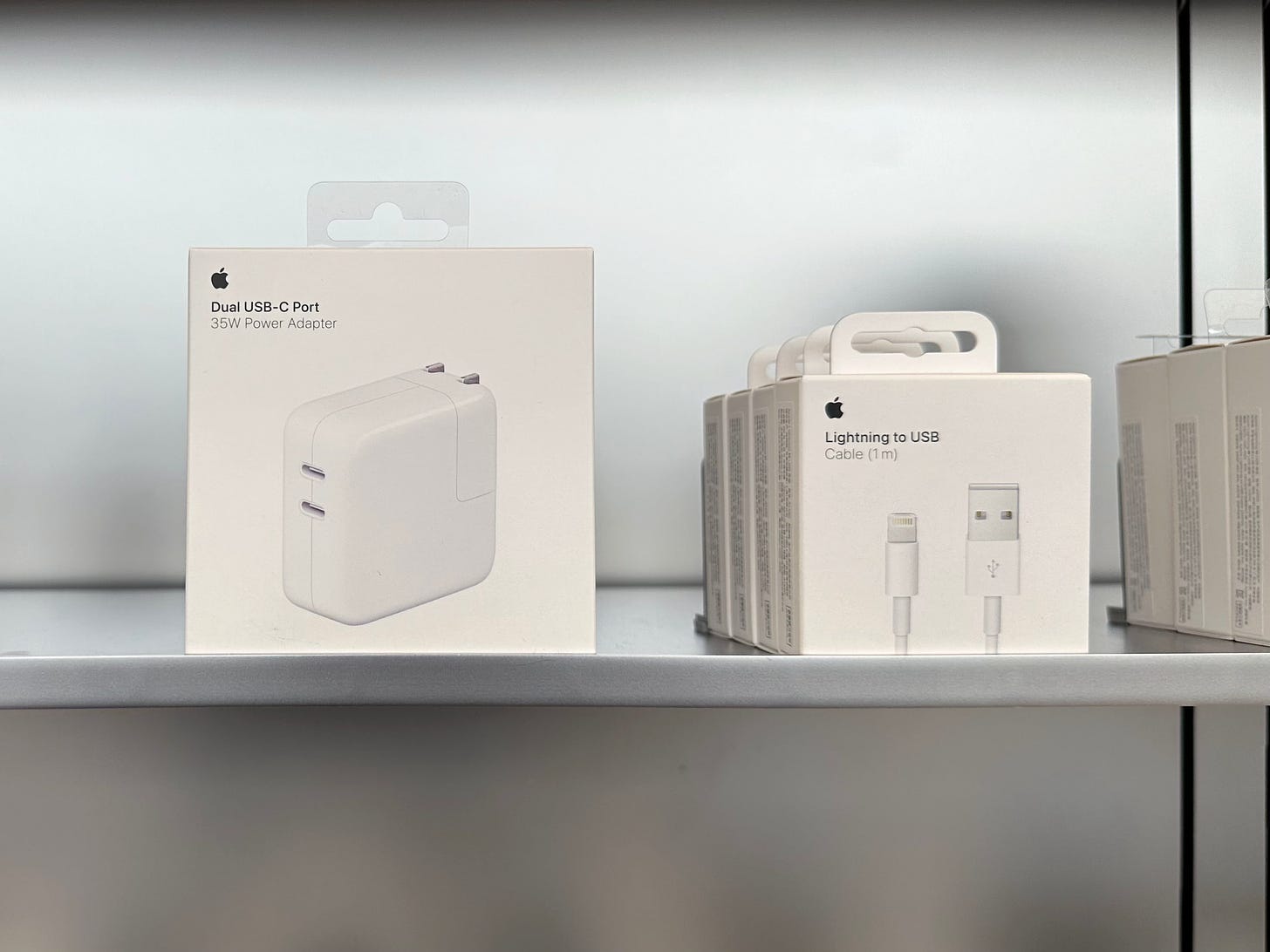 Old and new Apple charging accessories. The old box has a plastic tag, and the new box has a paper tag.