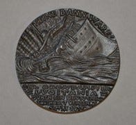 A photograph of the Lusitania Medal, showing the ship sinking below the waves.