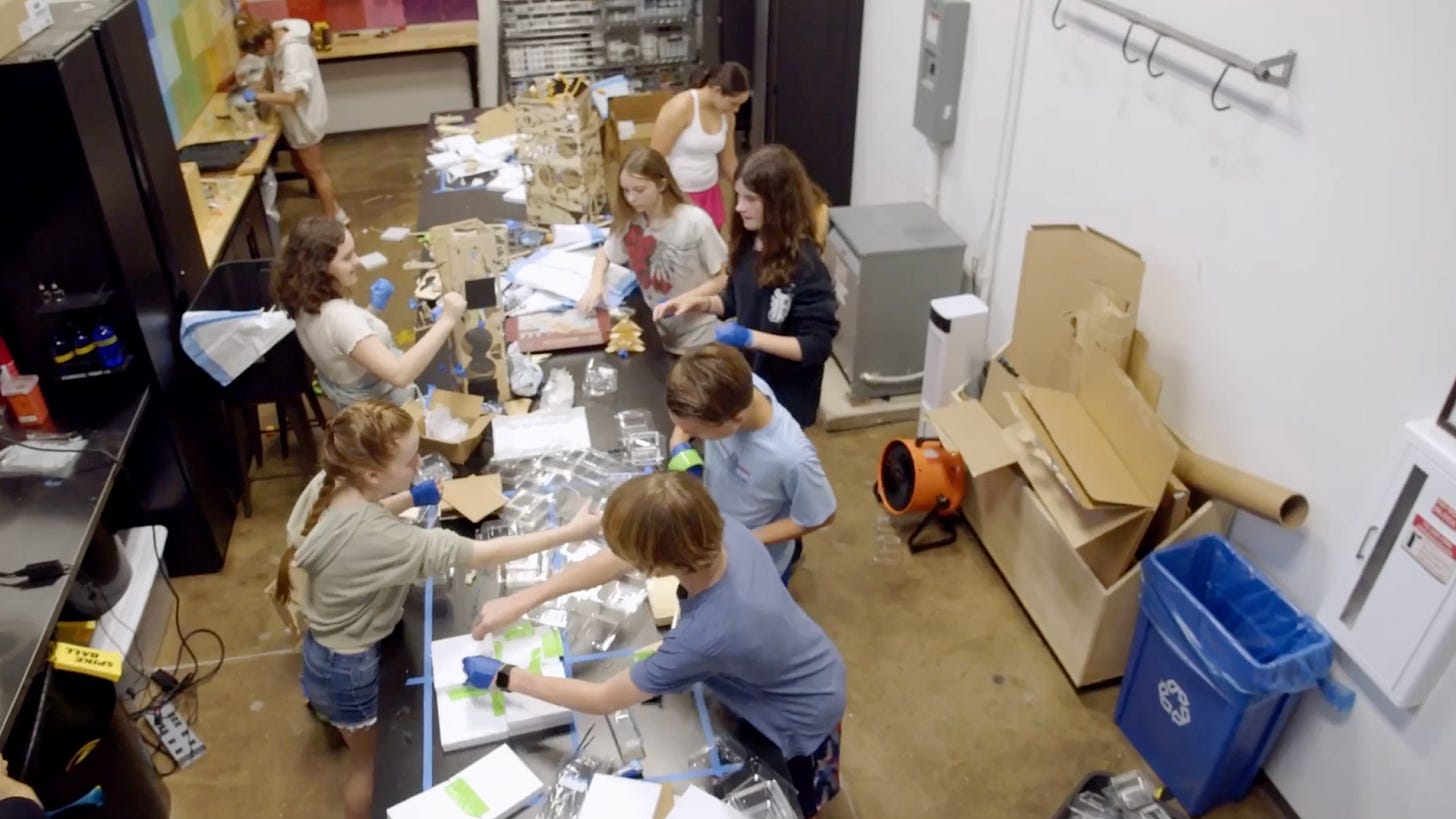 An image of grade school kids making cool stuff in a lab full of construction equipment.