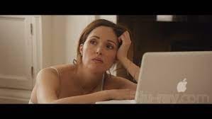 Still from Juliet Naked showing Rose Byrne crouched by the bed wearing only her underwear, listening to the Tucker Crowe album through her Macbook