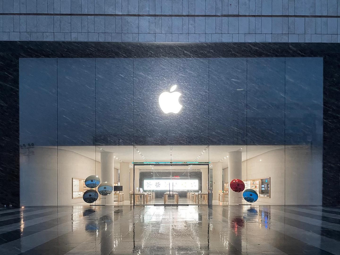 The exterior of Apple Changsha during a snowstorm. iPhone window displays are placed prominently at the front of the store.