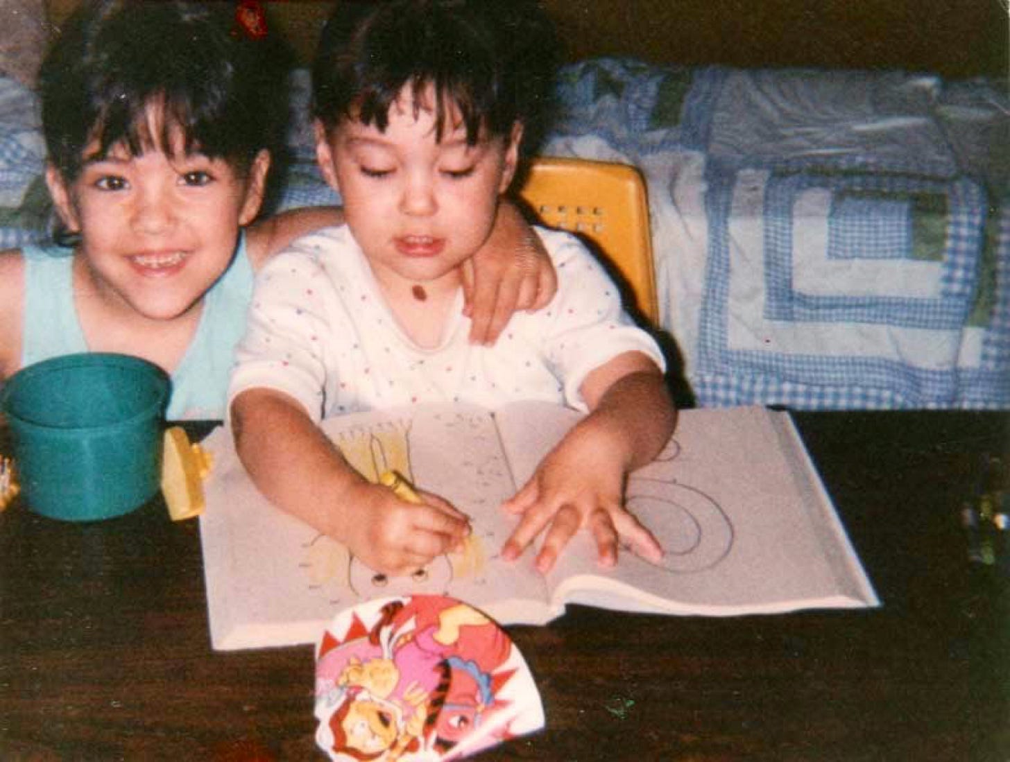 Old 90s photo of two kids, one colouring in a colouring book