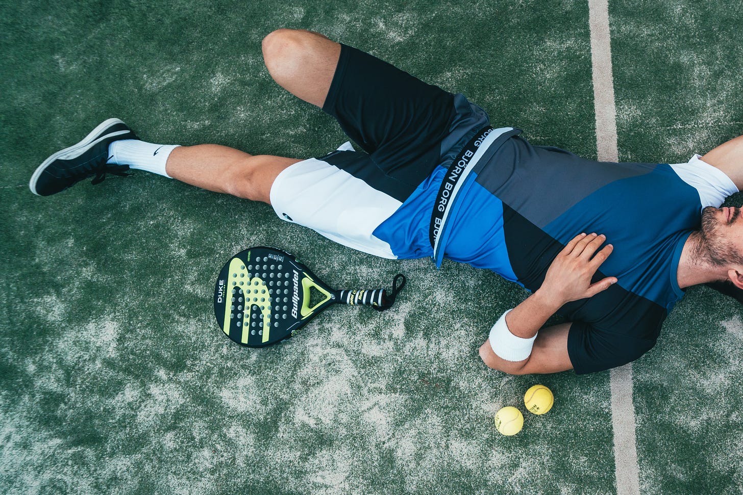 Male tennis player lying exhausted on the groud