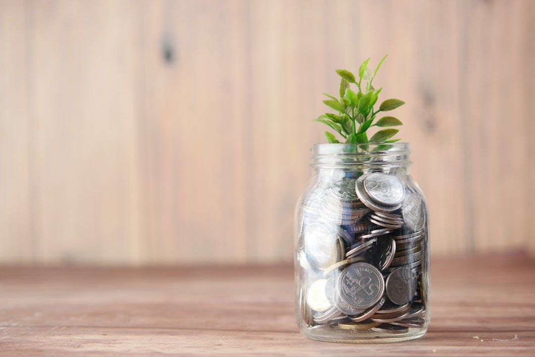 a glass jar filled with coins and a plant