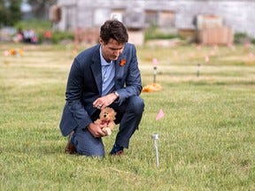 Prime Minister Justin Trudeau lays a teddy bear at a small flag marking one of 751 unmarked graves discovered at the site of the former Marieval Indian Residential School on the Cowessess First Nation in Saskatchewan, on July 6.