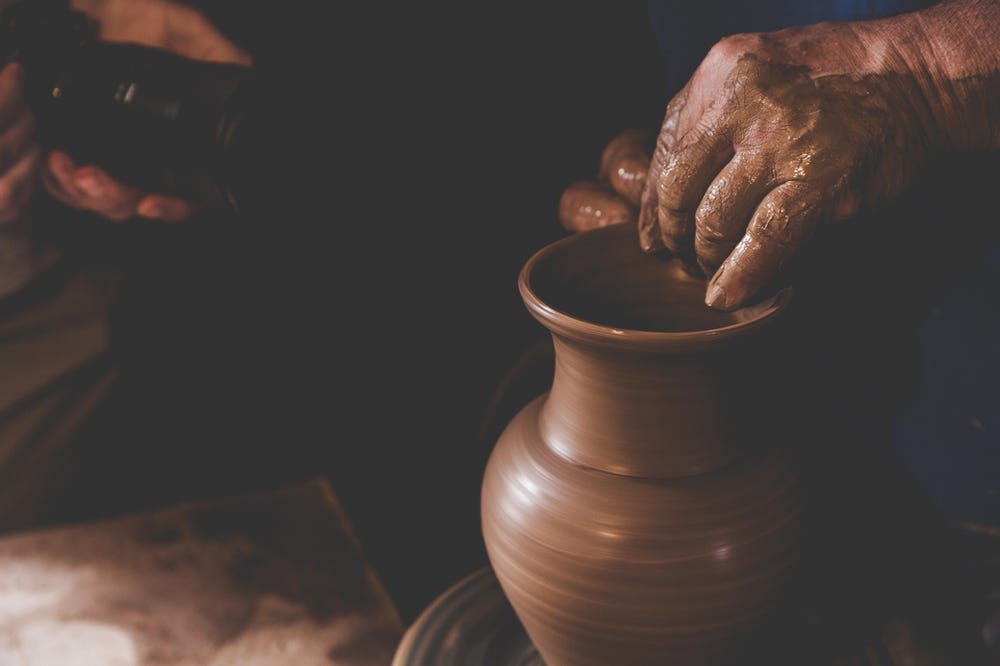 Potter molding clay into vase.