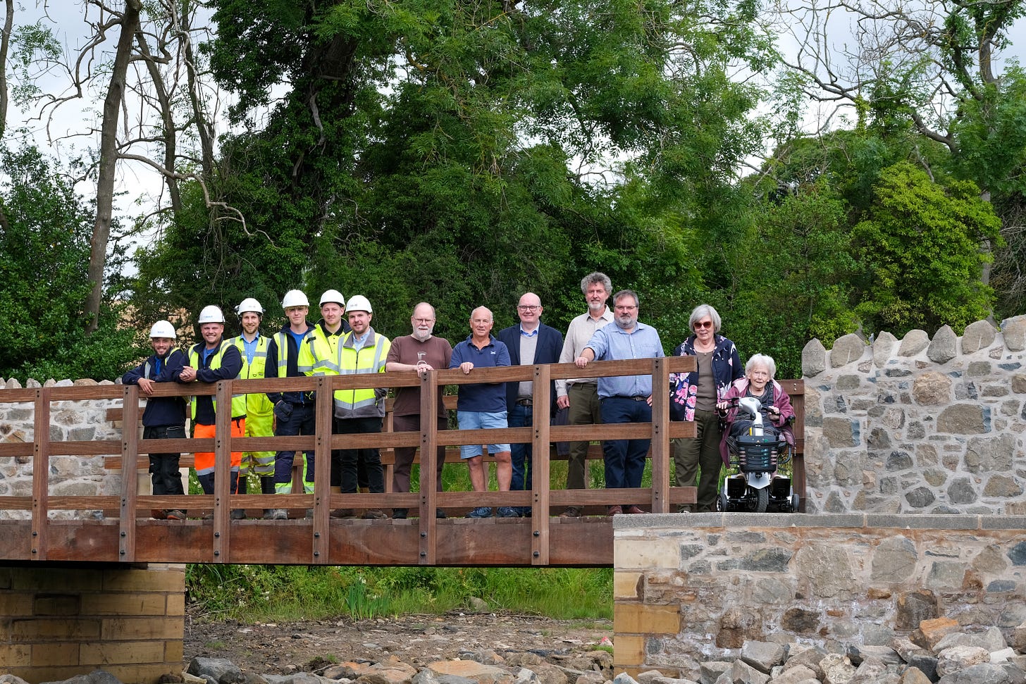 Construction company and Fife Council staff standing on the new wooden footbridge in Abedour Harbour