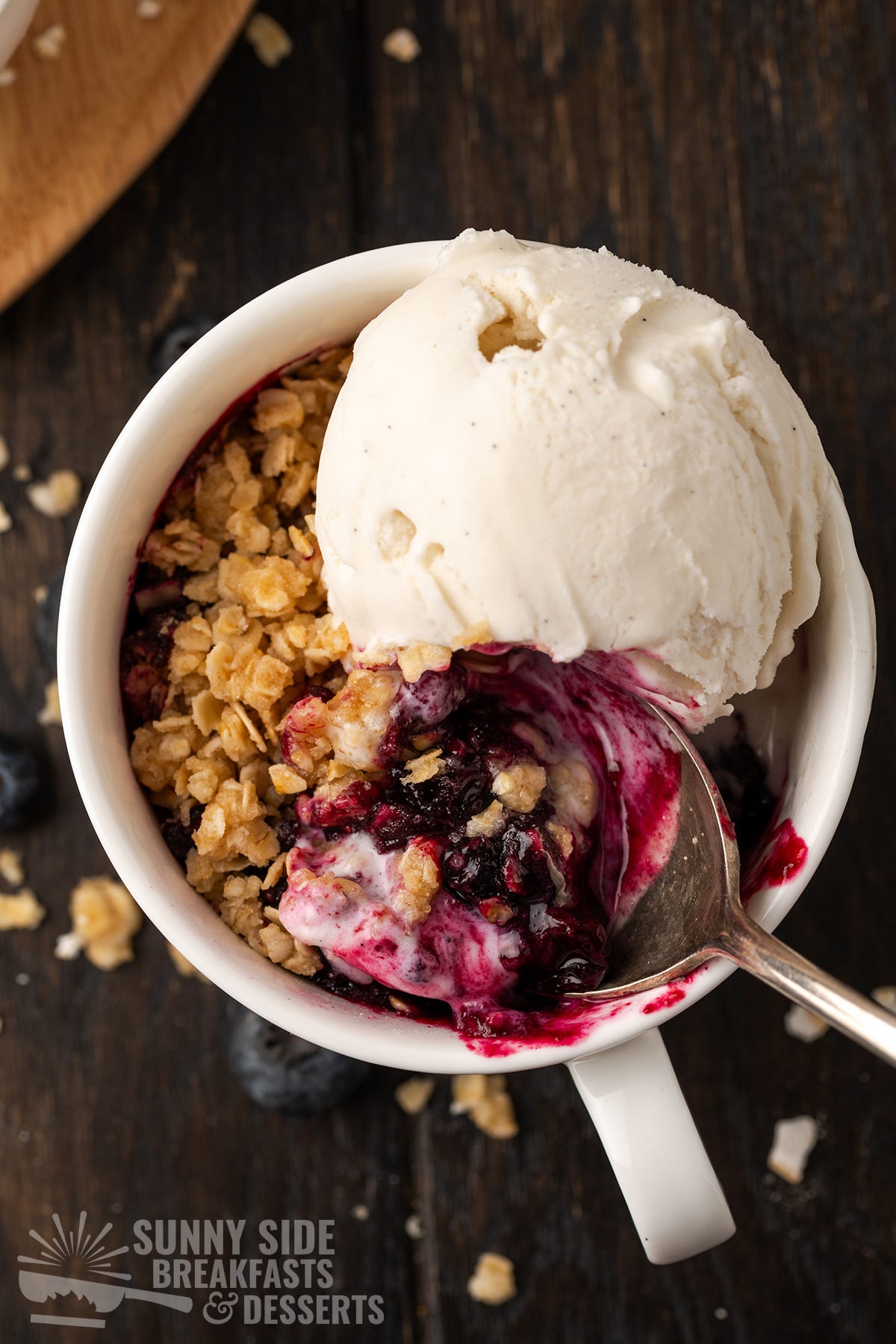 Blueberry crisp in a mug with ice cream.