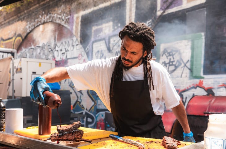 A chef pouring sauce over a cooked joint of meat