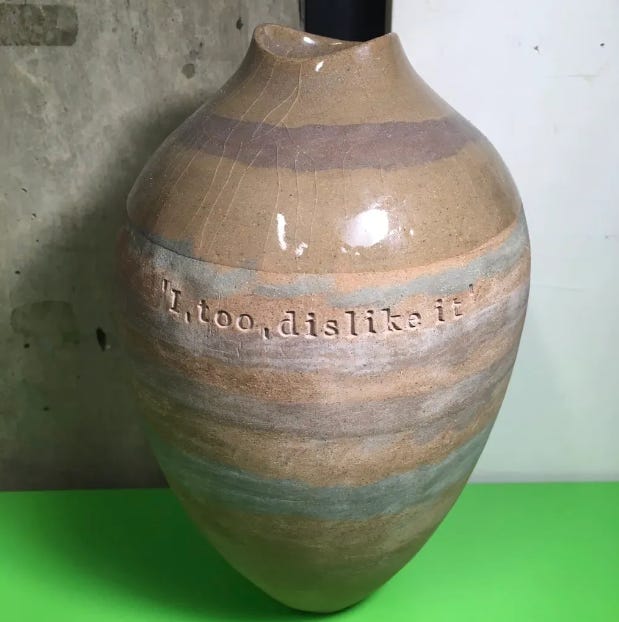 A banded clay pot imprinted with the words "I, too, dislike it"