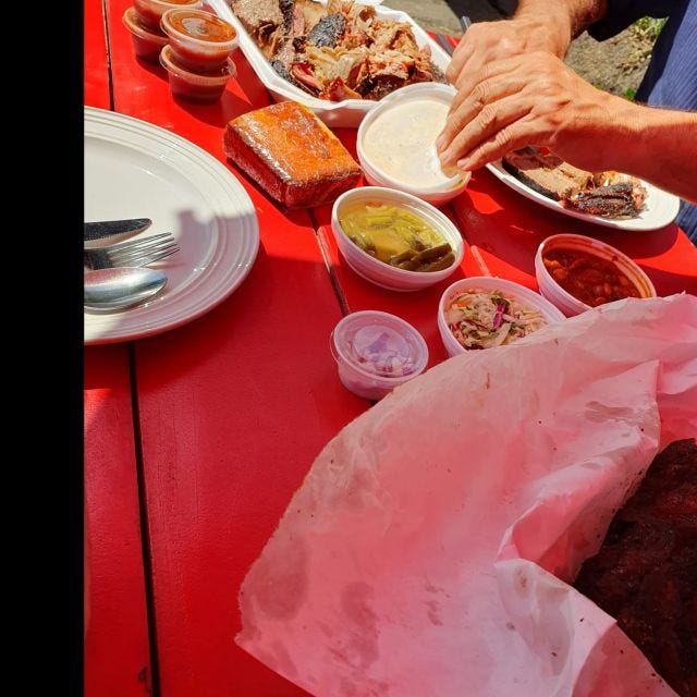 the barbecue brisket and beef rib, plus fixings, on a bright red table in bright sunshine (feat. my dad's hands), at Whisky Flats in San Pedro.