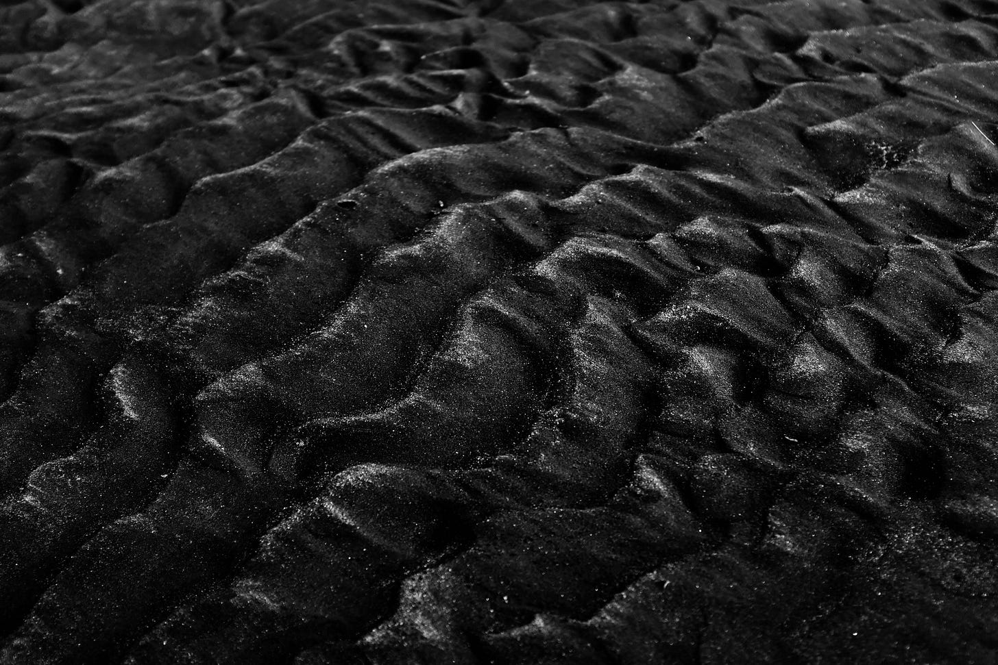 Grayscale photo of sand in successive waves