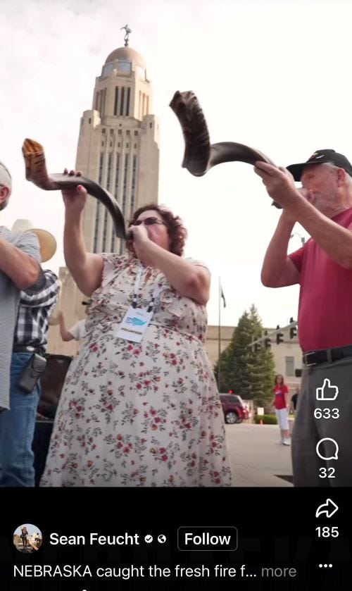 Two people blow shofars on stage at a Sean Feucht rally
