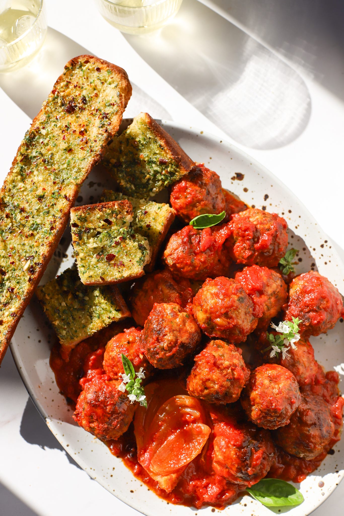 Platter of meatballs in tomato sauce with garlic bread on the side