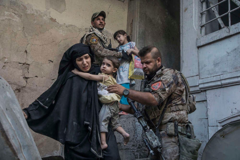 Deux femmes et leurs enfants sont évacués par des soldats.