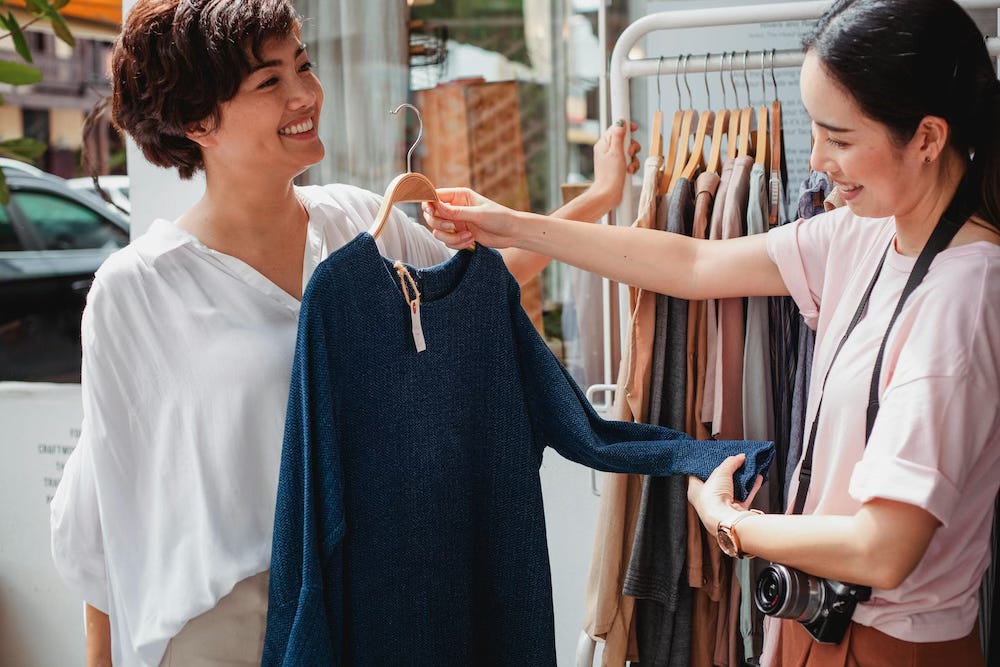 Two women looking at a jumper in a shop Two women looking at a jumper in a shop