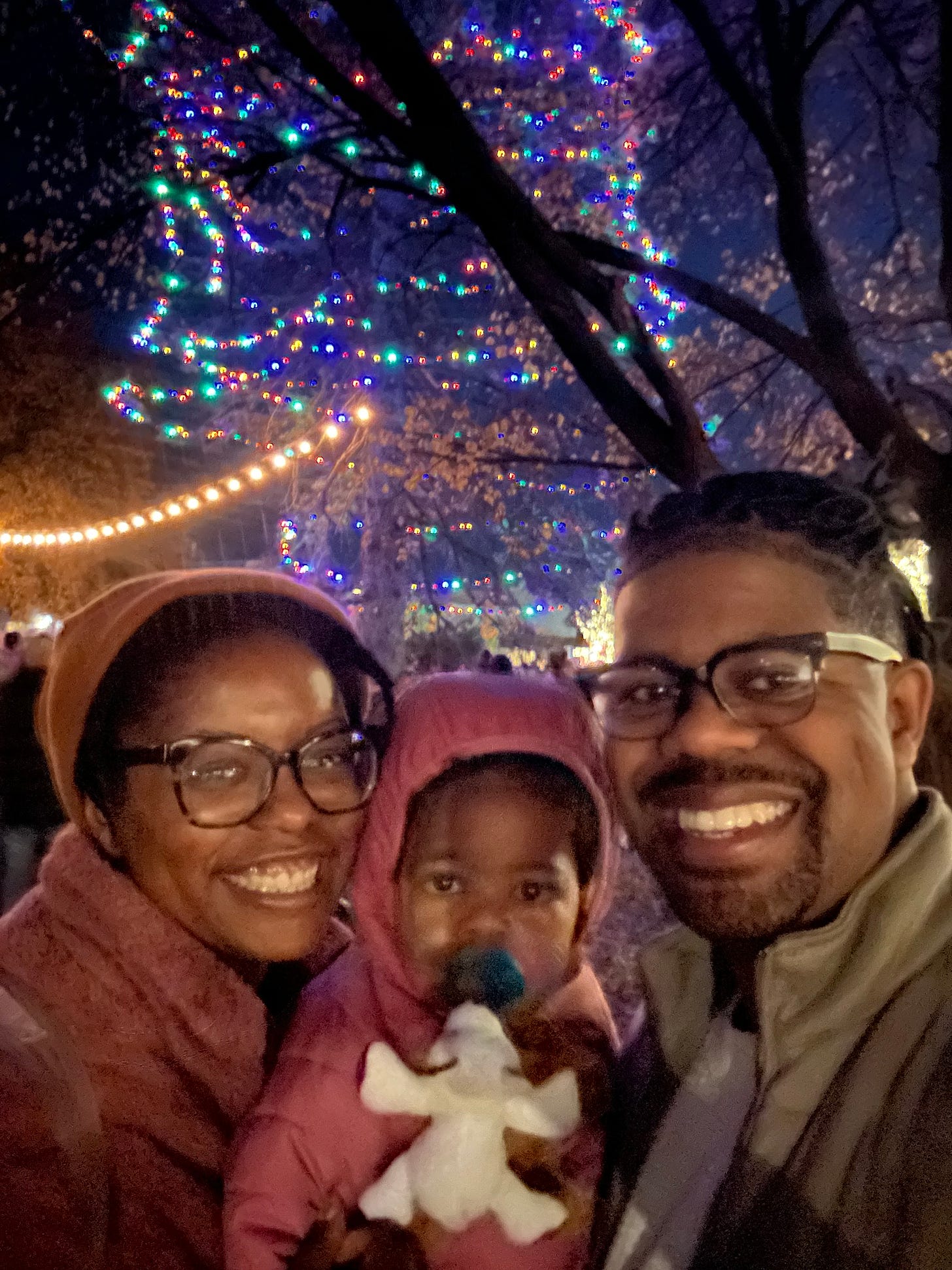 A picture of a Black family in front of a brightly colored tree.