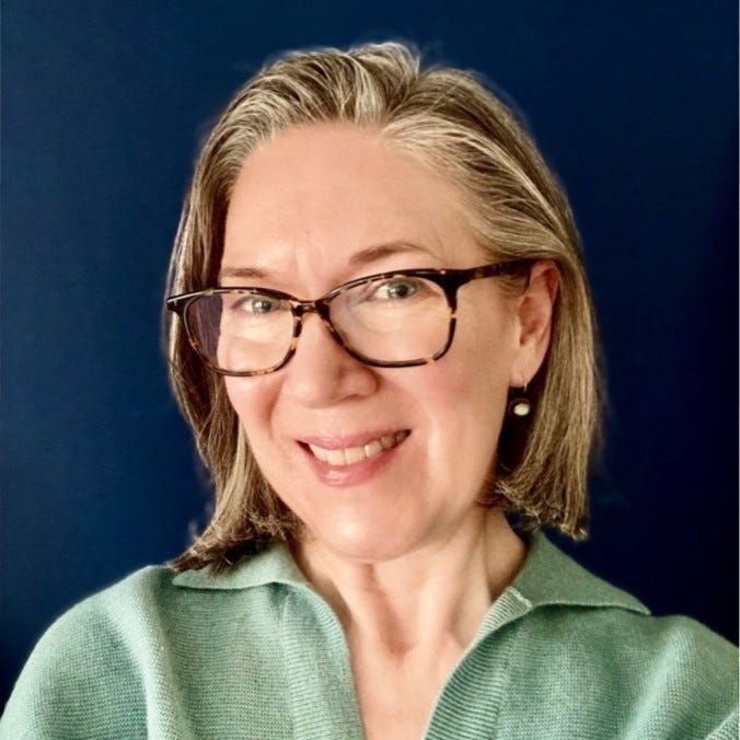 headshot of a professional woman with glasses and a green sweater