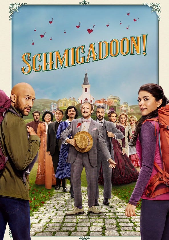Schmigadoon! poster featuring two people in modern clothes looking back at the viewer with confused expressions while standing in front of a group of people dressed in 1950s clothing looking cheese and cheerful