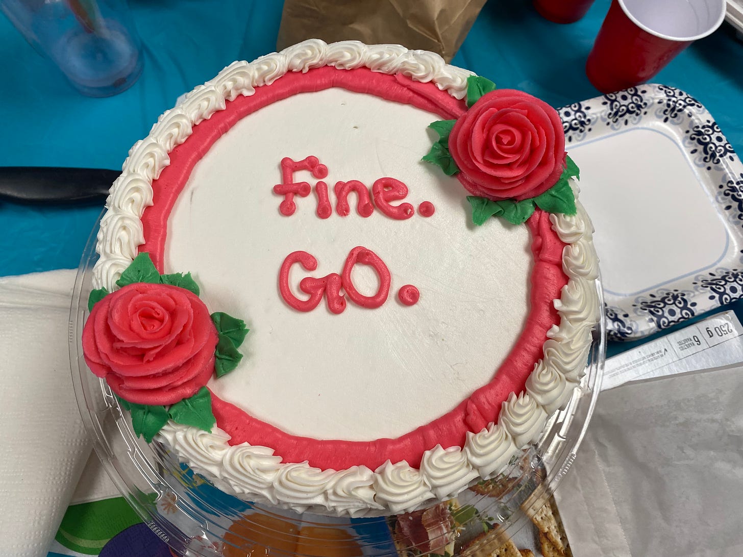 A white birthday cake with "Fine. GO." written on it.