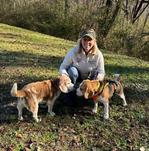 Woman holding her tracking Beagle and the elderly Beagle her dog just found