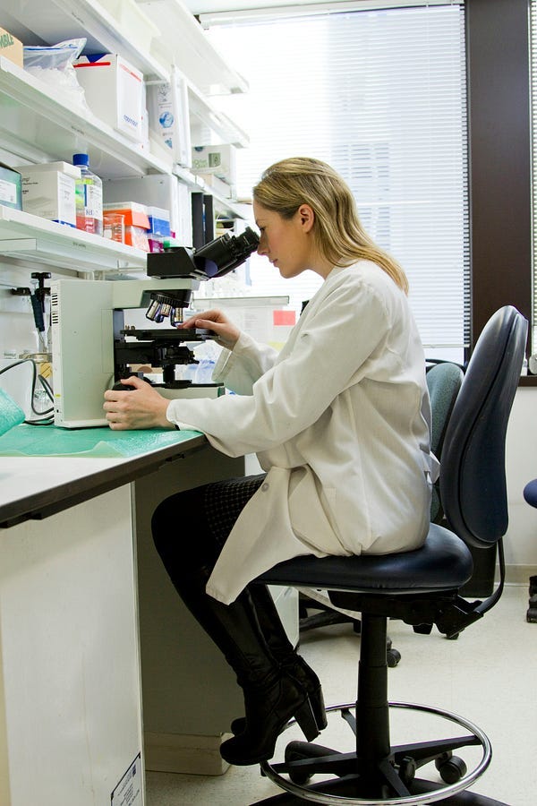 Woman in a laboratory looking through a microscope.