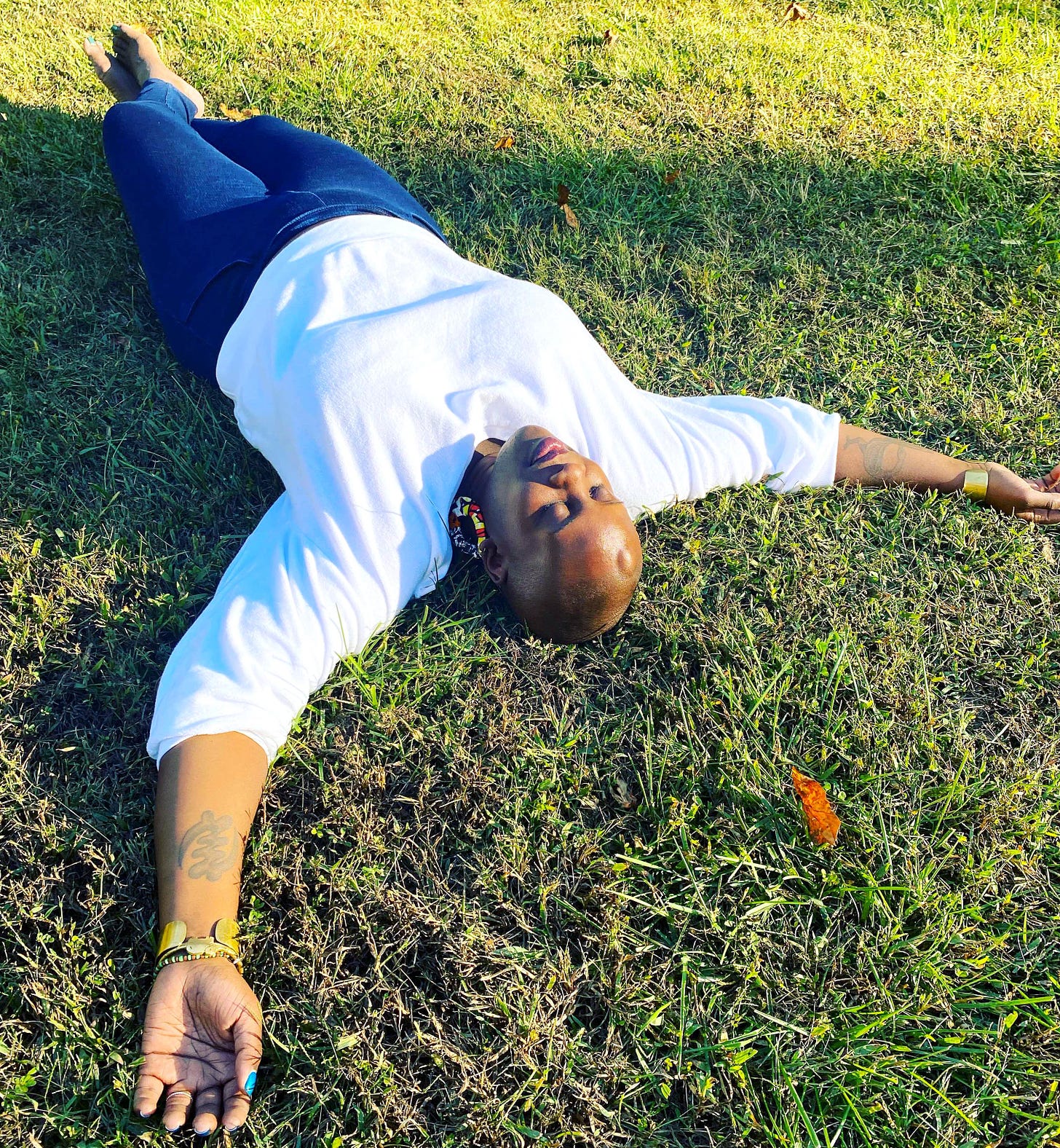 Kyndra lying on her back in the grass, eyes closed, at peace