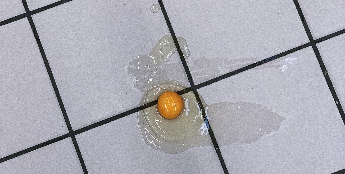 A cracked egg on the tile floor