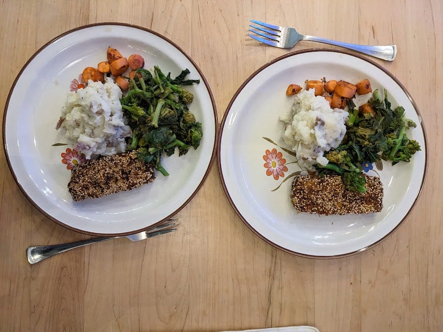 two plates of sesame-crusted tofu, caulipots, carrots and kale