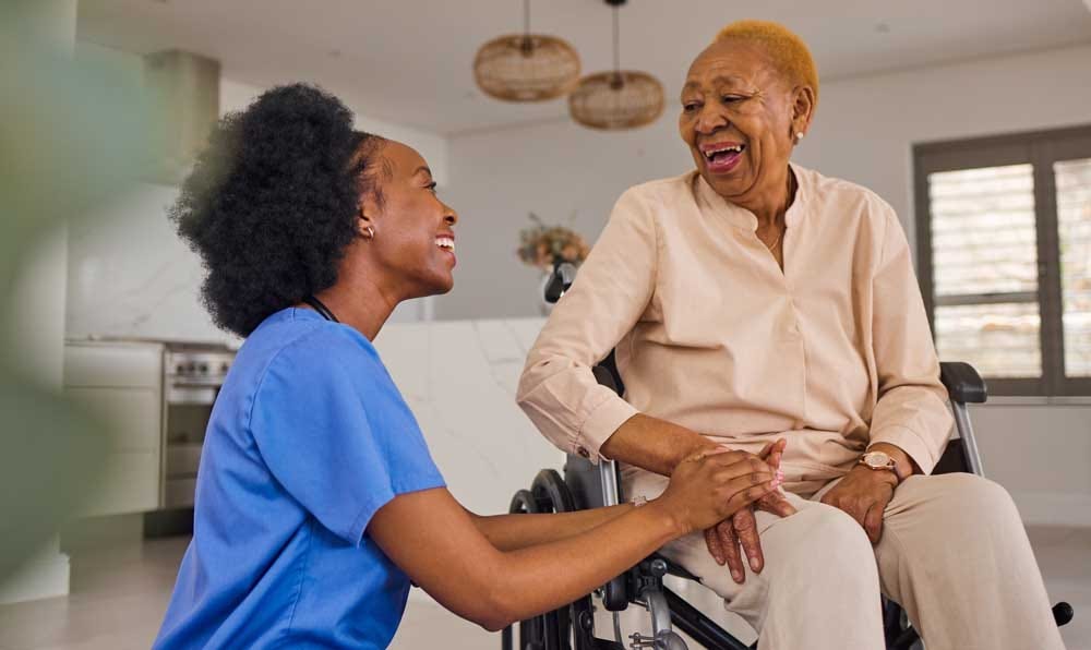 Lively elder woman enjoying nurse’s attention & care in her independent living home.