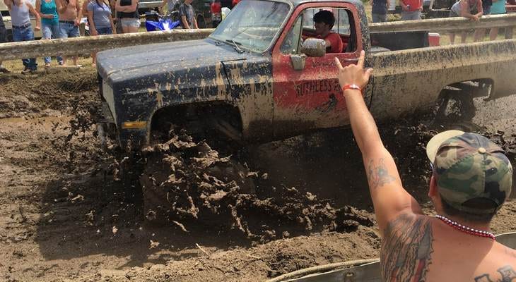 Spectators cheer as a pickup truck splashes through mud at an event formerly called the Redneck Olympics on Saturday, July 30, 2016, in Hebron, Maine. The organizer now calls the event