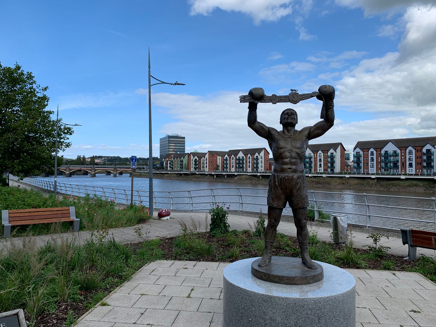 Newport's Rocky's statue in a community space with the river Usk on the background