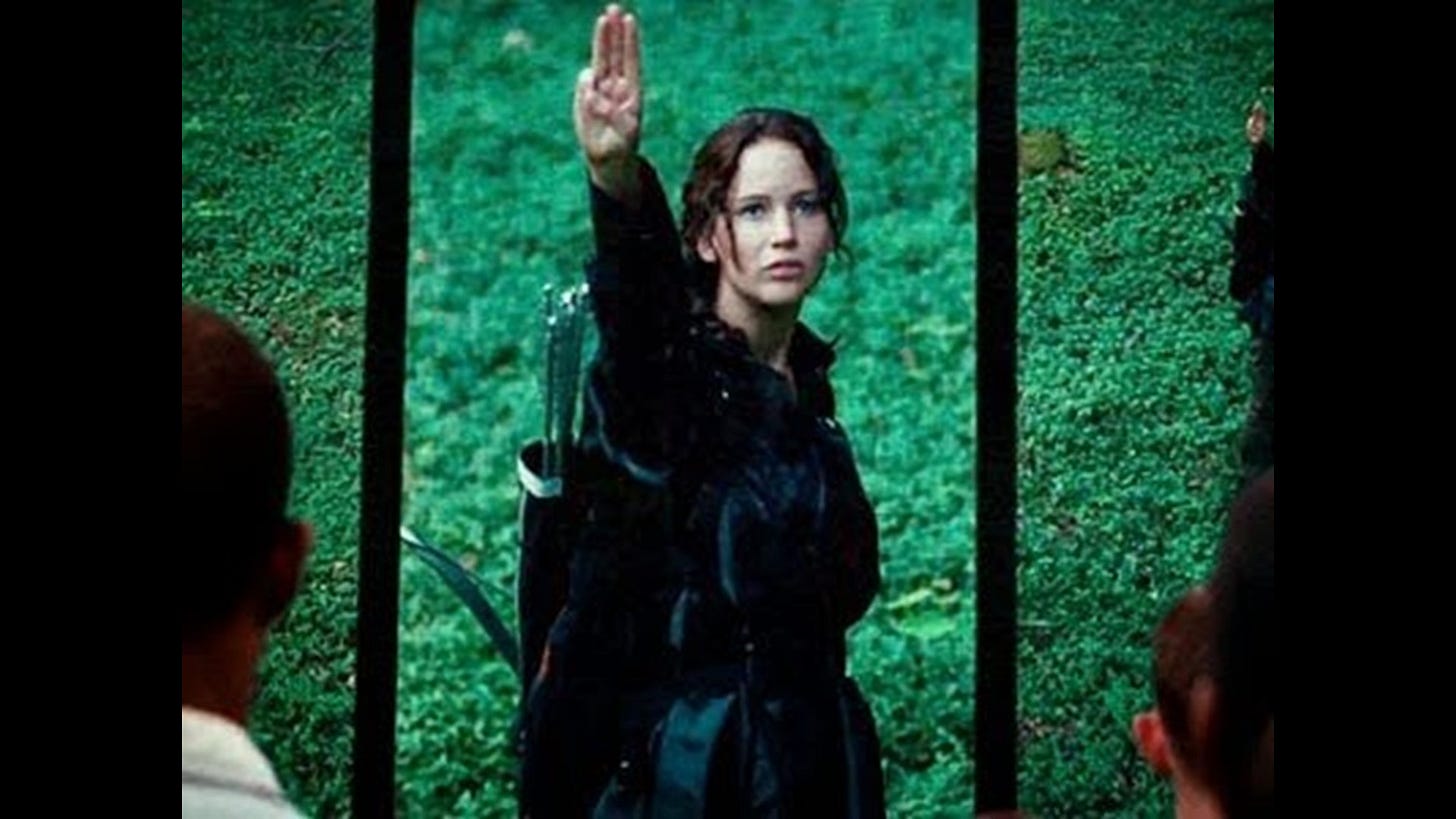 Jennifer Lawrence as Katniss Everdeen gives the Hunger Games salute.