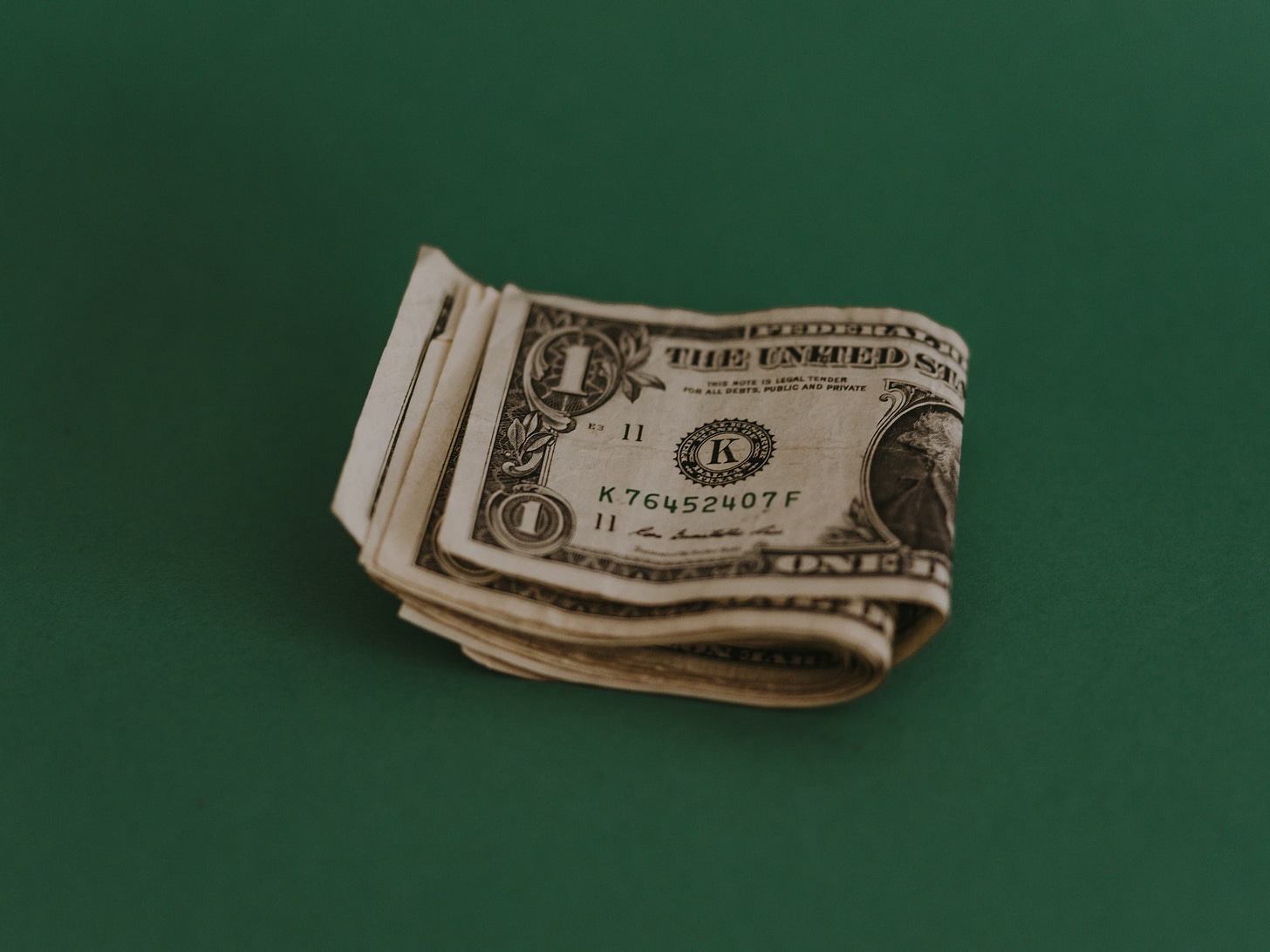 An image of folded dollar bills on a green background An image of folded dollar bills on a green background