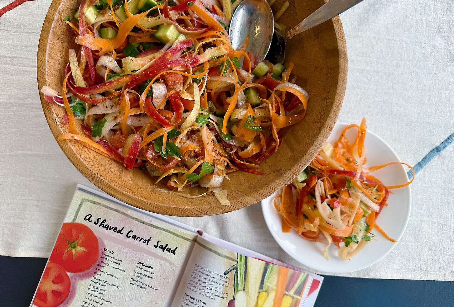 Image of a large bowl of the shaved carrot salad from "Love Letter to a garden" with the book open to the page with the recipe.
