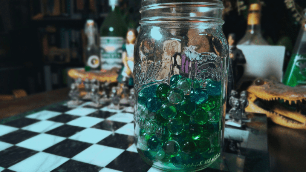 Blue and green marbles in a mason jar on a chess table