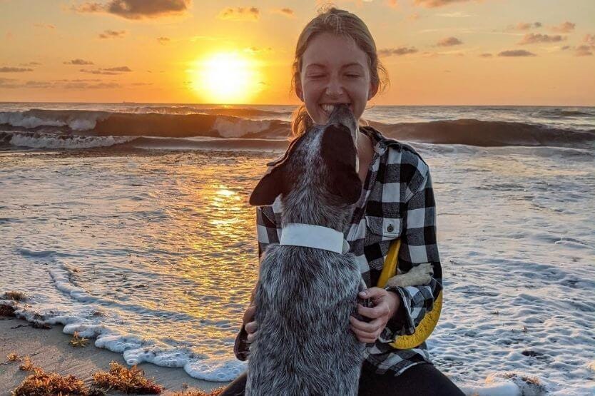 Scout the blue heeler licking her owner's face at sunrise on the dog-friendly stretch of Cocoa Beach in Florida