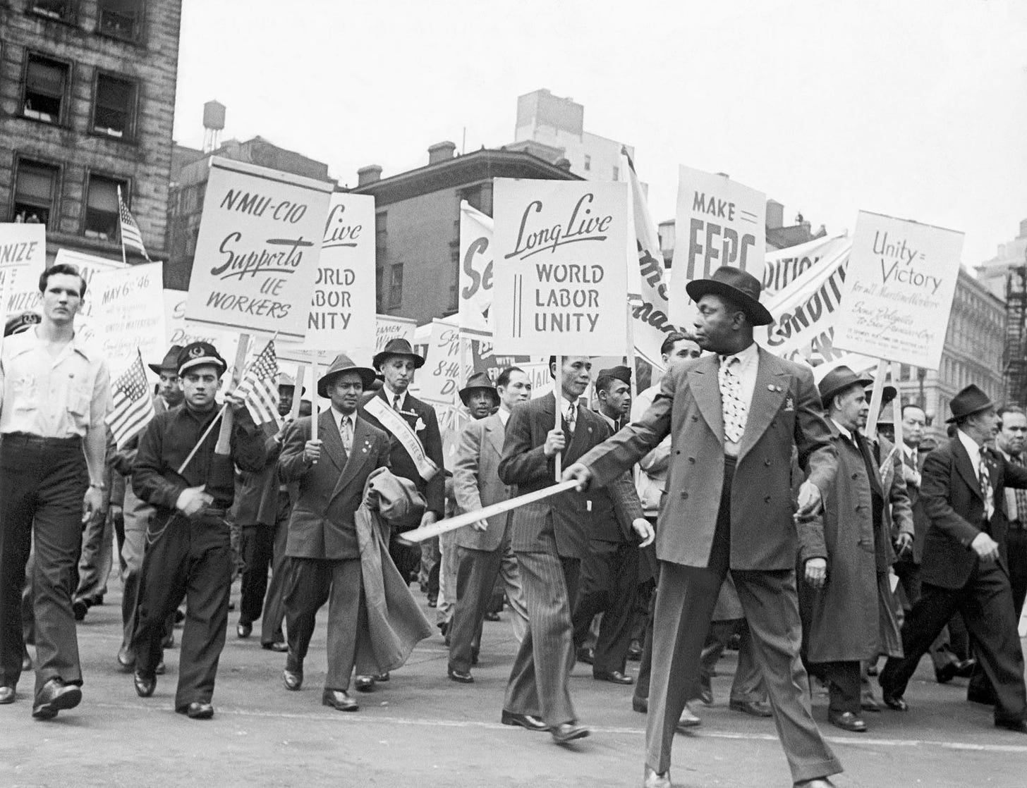 Workers of various affiliations march together at a 1946 May Day parade in New York City. Men with union placards 