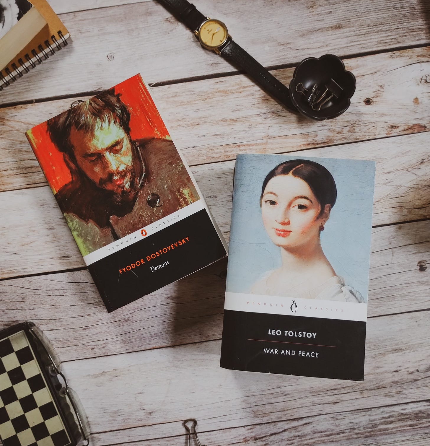 Penguin black classics, War and Peace by Leo Tolstoy and Demons by Fyodor Dostoevsky, on a wooden table