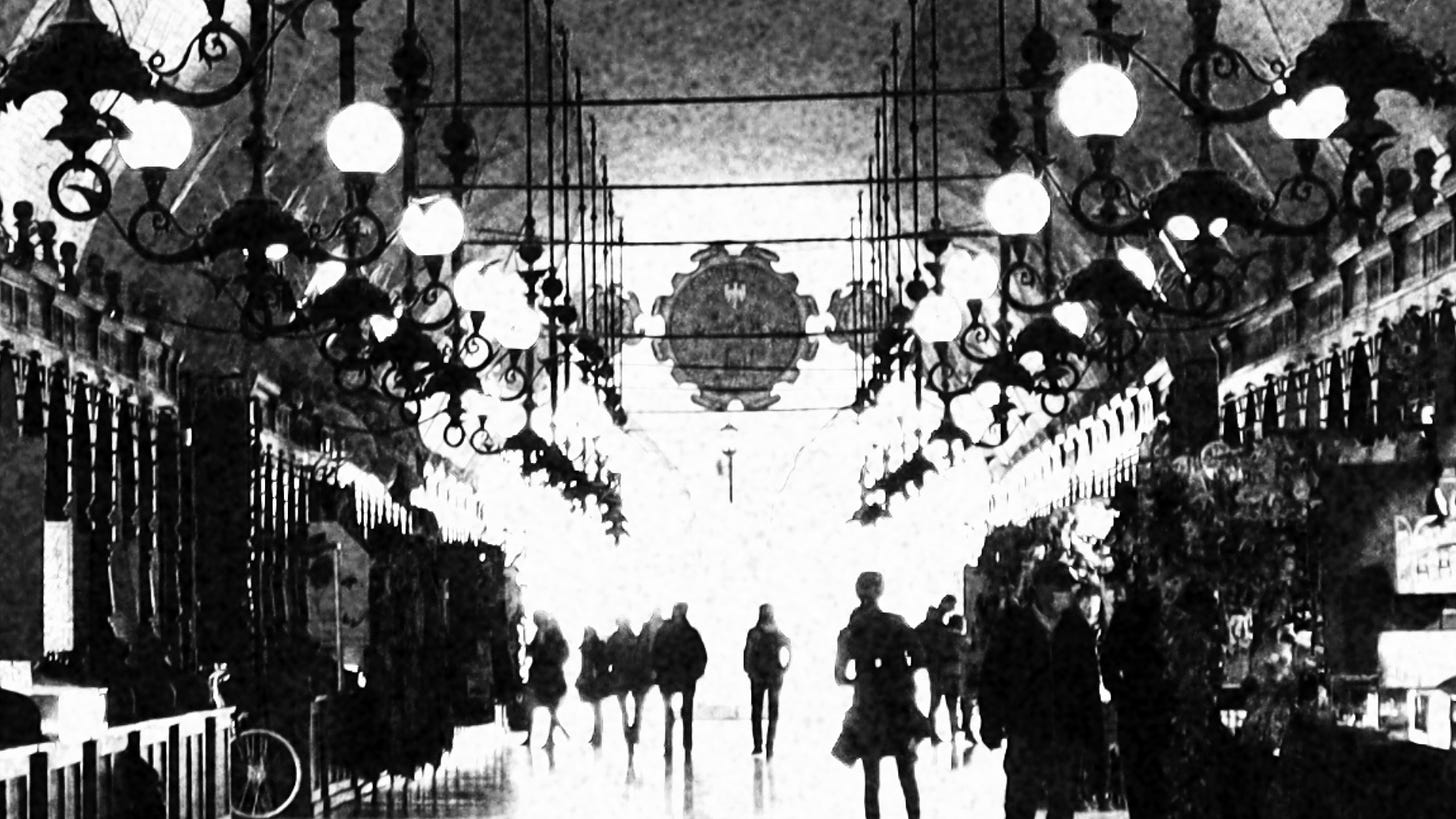 a grainy black and white photograph of Krakowskie Sukiennice, a row of lamps and stalls, silhouettes of people disappearing into the light at the centre   