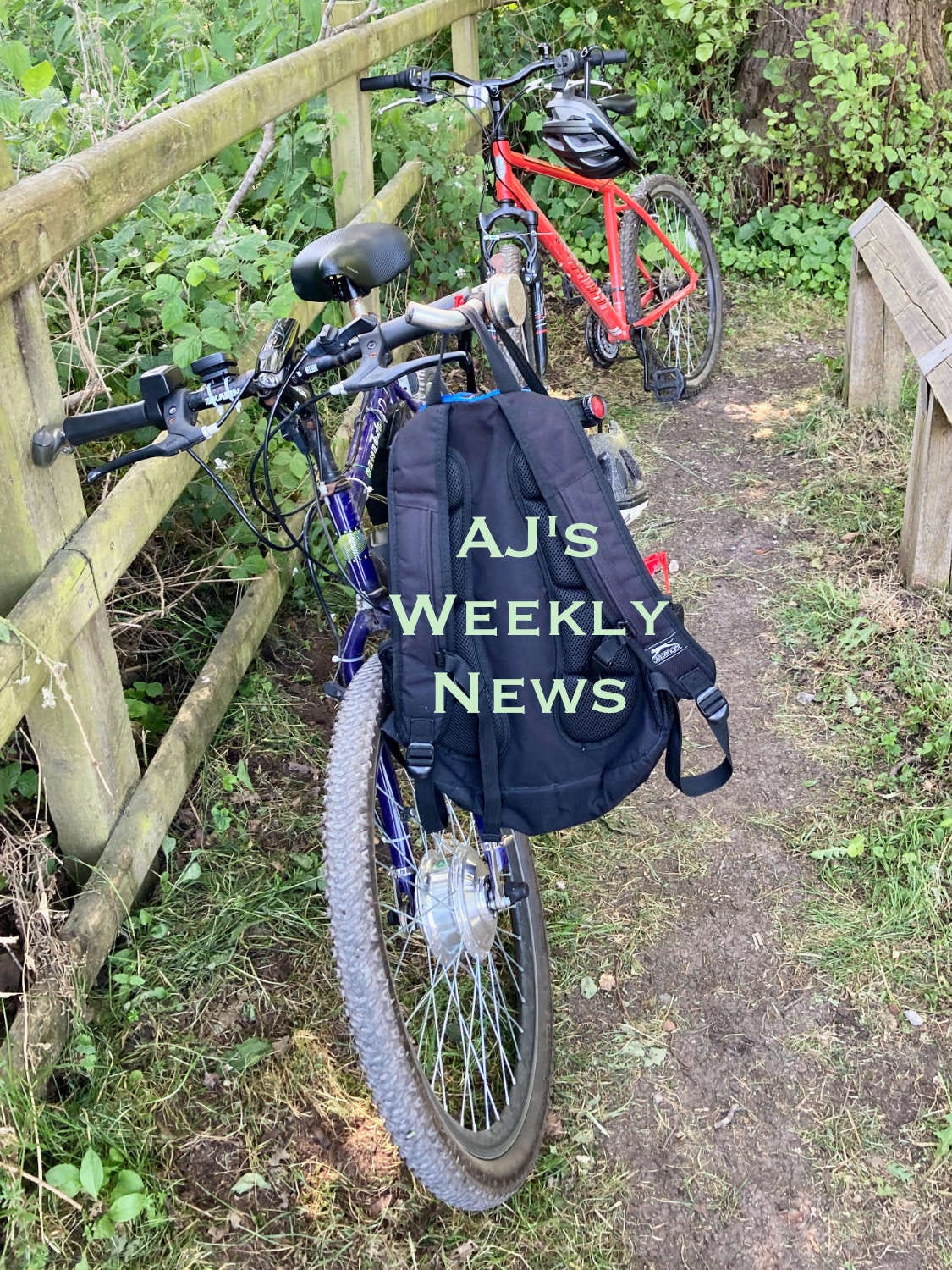 Two bicycles leaning on a fence in the countryside. The caption reads, "AJ's Weekly News"