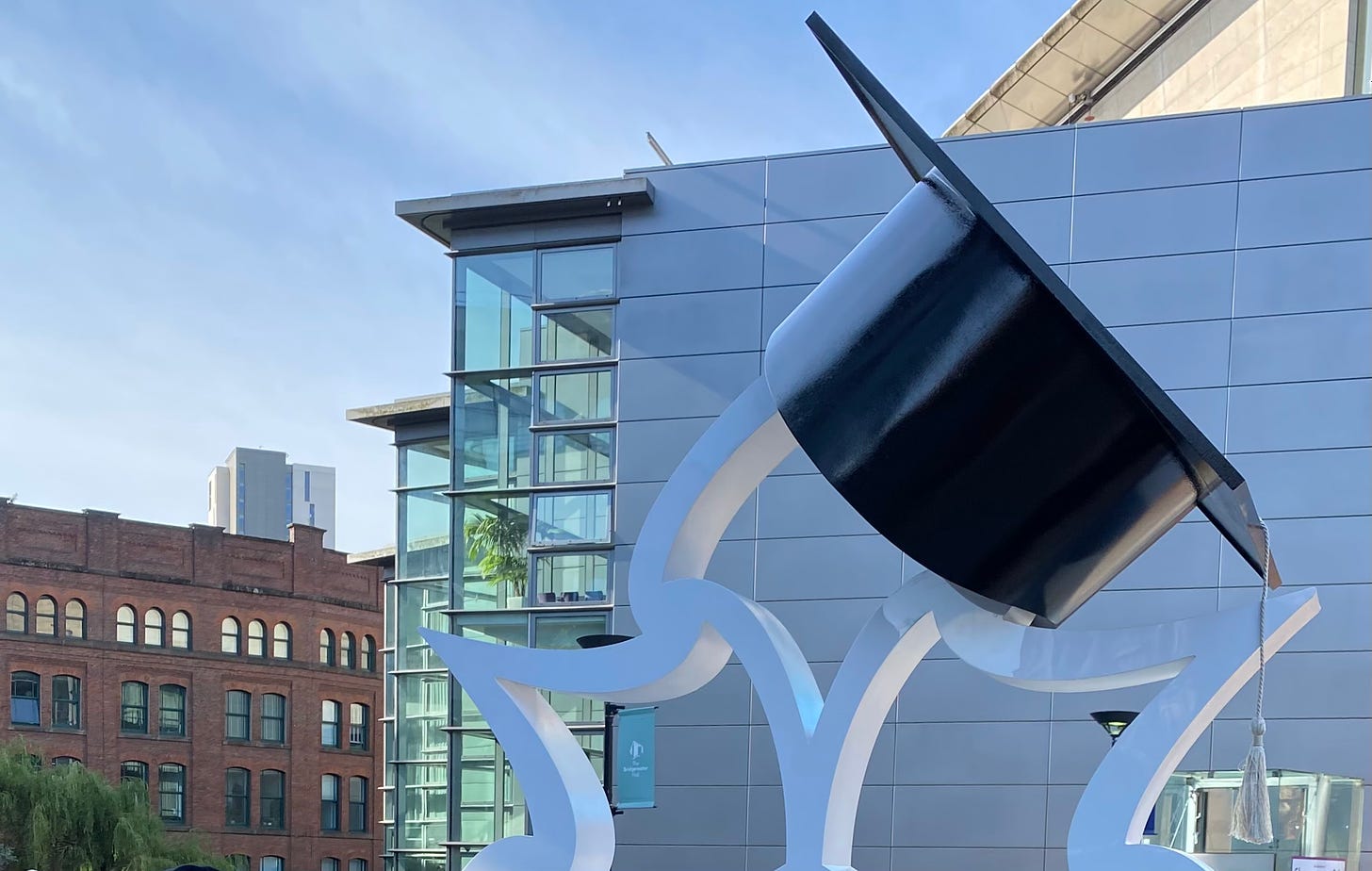 Street scene in Manchester England with sculpture depicting university graduation.